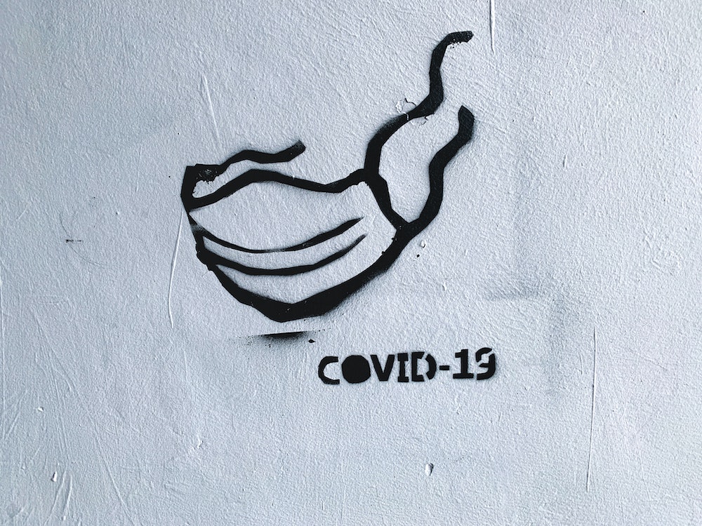 Photo of a graffiti of a face mask written COVID19.